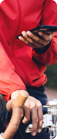 Delivery rider in a red jacket holding a phone.